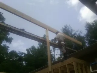 Carpenter setting a ridge beam over a new addition frame — Ice Dam Removal by Roofing Brothers in Risingsun