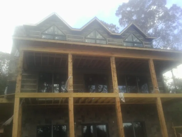 Dormers and porch framing on a large log home under construction — Roof Coating work by our crew in Risingsun