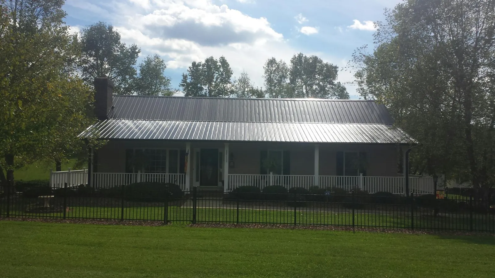 Gray metal roof on a brick ranch with a full width front porch — Gutter Guard Installation work by our crew in Risingsun