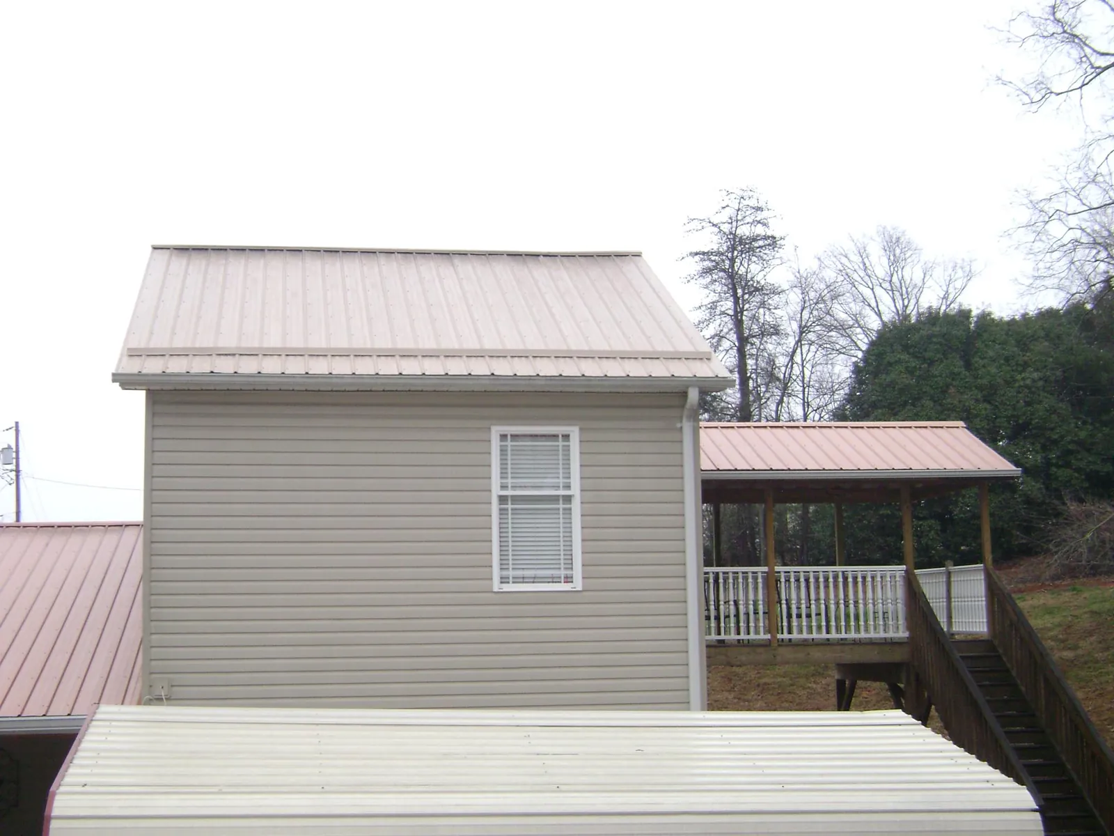 Tan metal roofs on a two story addition and attached porch, from a Roof Replacement job in Risingsun
