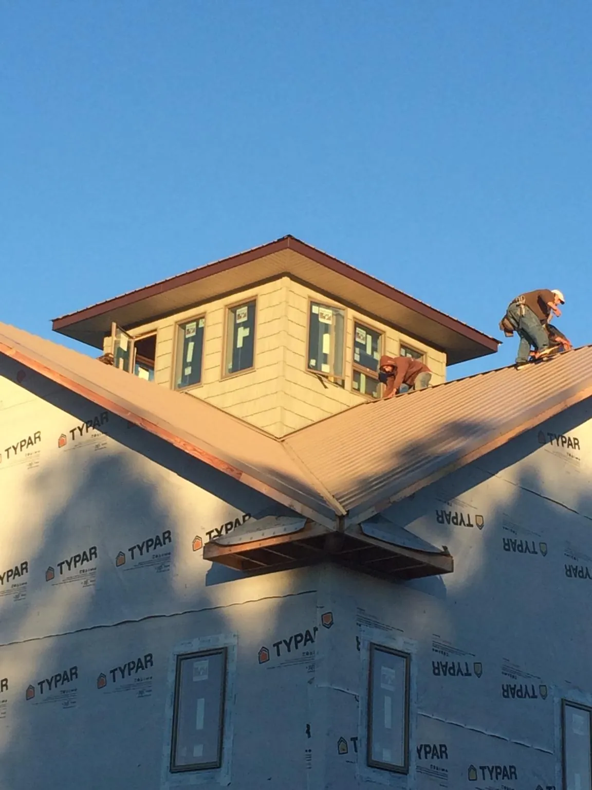 Roofers working around a rooftop cupola on a new metal roof at sunset — Roof Waterproofing in Risingsun by Roofing Brothers